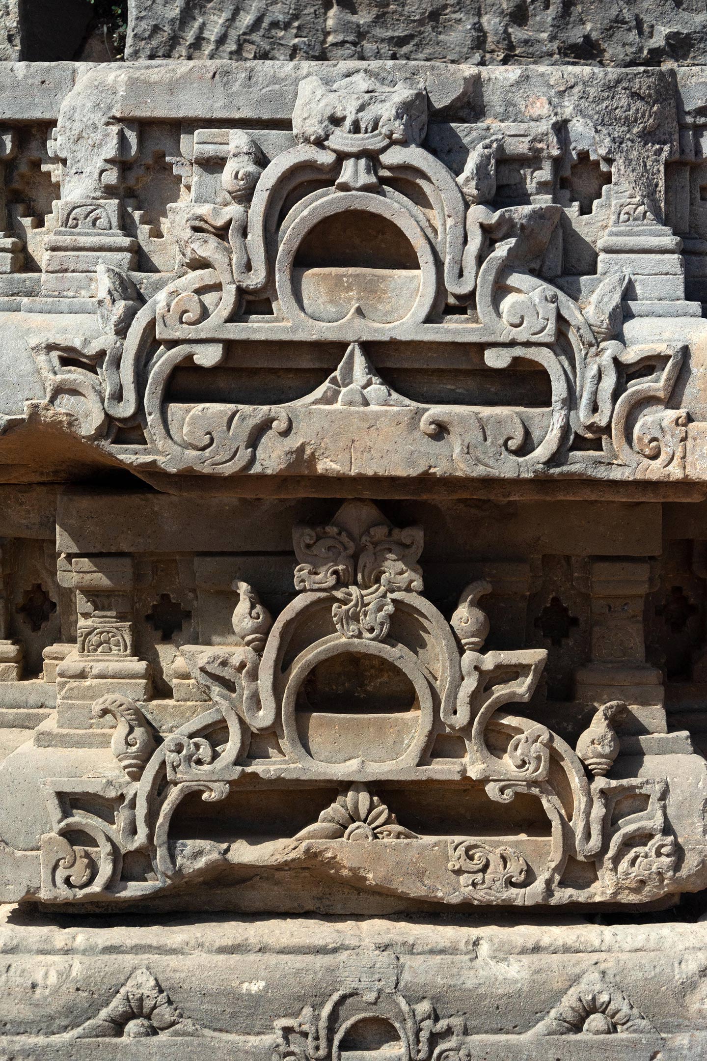 Broken debris from the original temple assembled on the northeast face of the adhisthana. Seen in the carvings are the split gavaksha motifs.