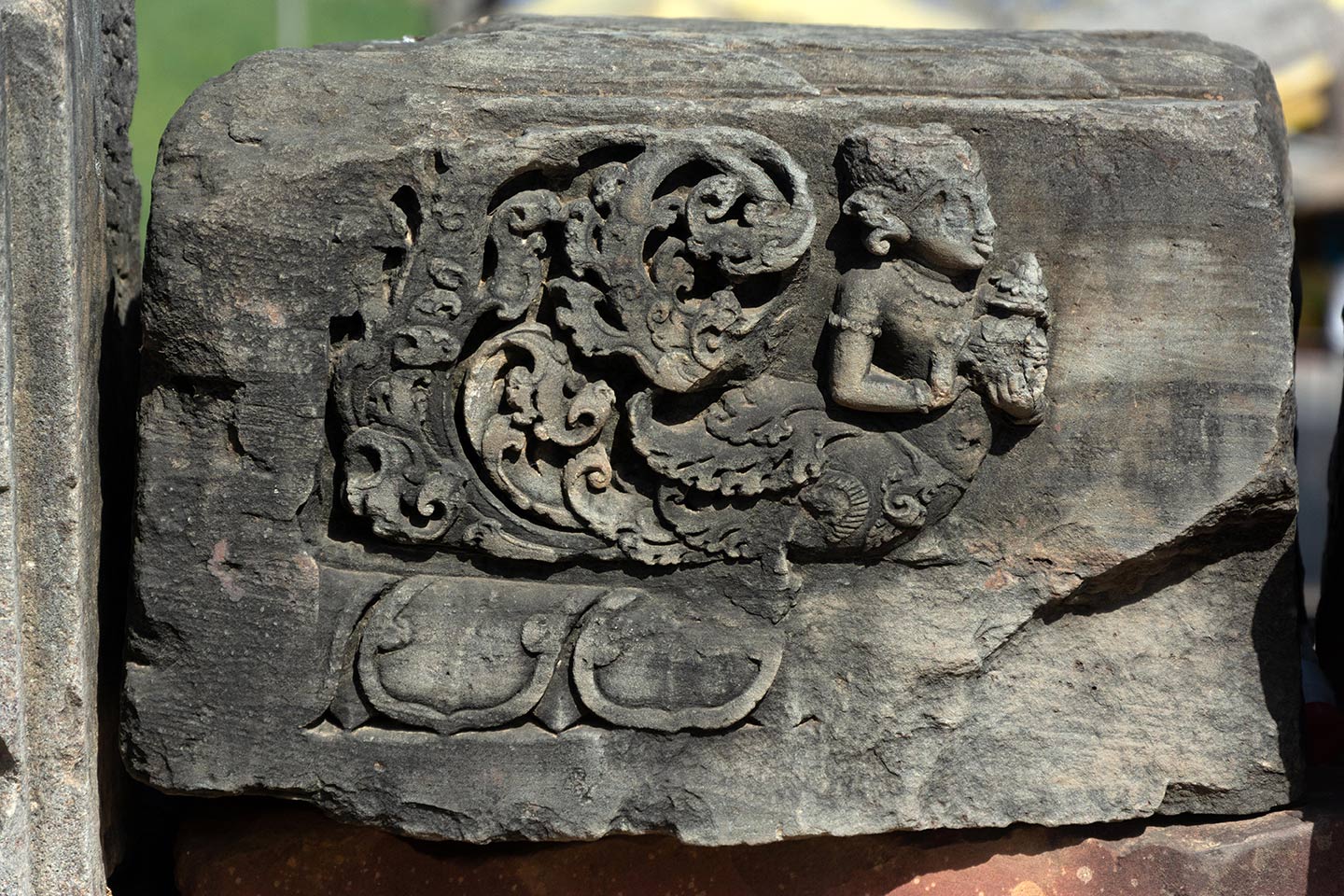 The carving features a kinnari holding a purna ghata (a symbol of abundance, prosperity, and fertility). The upper body of the kinnari is depicted with a female human figure and the lower body consists of a bird which forms a floral motif at the rear.