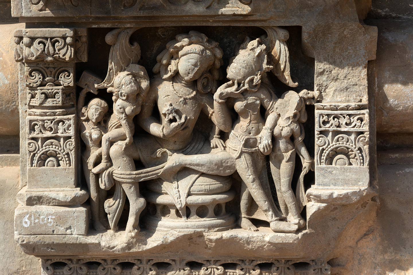 Sculptural panel depicting a couple (likely royal, based on their size and posture) seated on a circular throne and surrounded by female attendants. The scene depicts the couple admiring each other, in a moment of shringar rasa (romantic love).