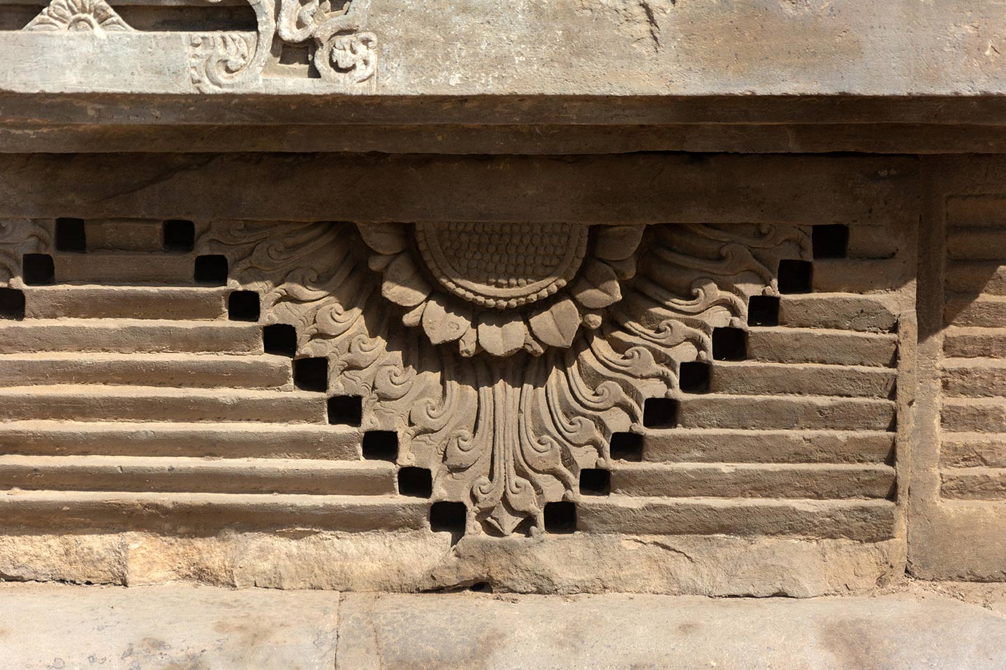 The architectural pattern used on the jagati or adhisthana of the temple with half floral motifs and step-like figures.
