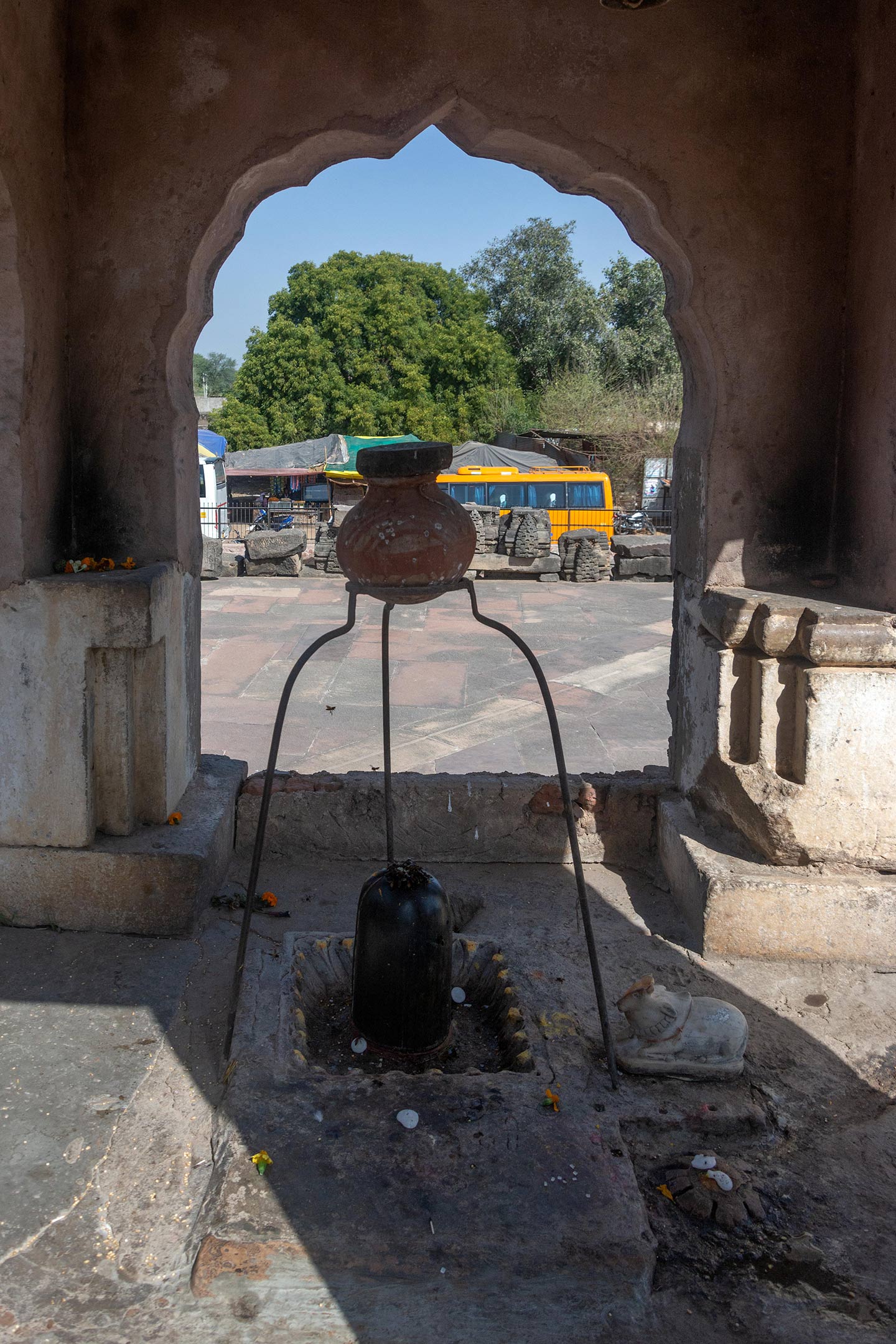 Off-centred to the right, facing the garbhagriha, sits a small shrine, possibly of recent construction. On a projected platform, further steps lead to the third level. Inside, they install a black stone Shiva lingam and place a Nandi figure next to it. A tripod holds an earthen pot that drips water over the Shiva lingam.