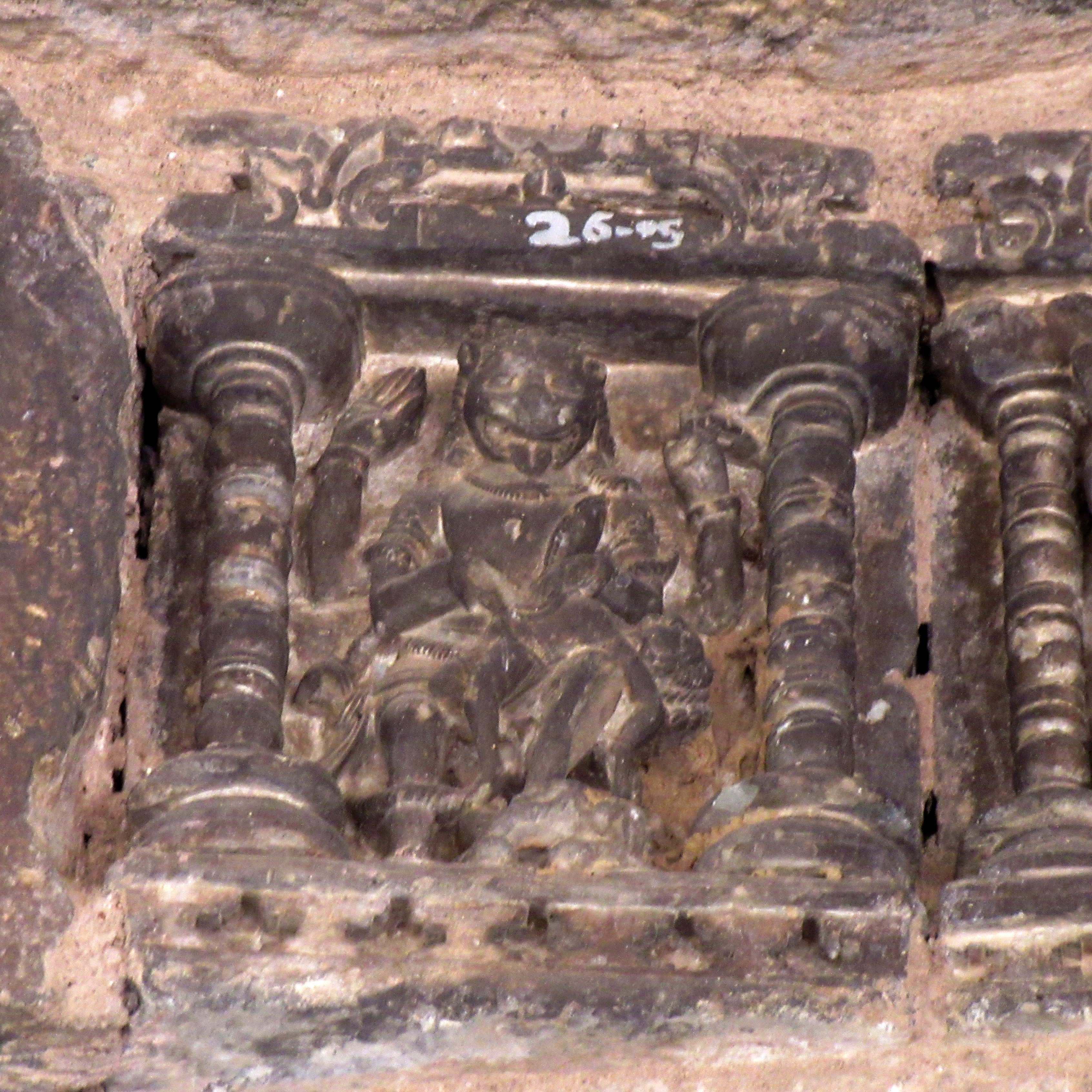 Image 11: The male deity, depicted with a lion's face, is four-armed. He holds a disc in his upper left hand and makes an abhaya mudra (hand gesture of assurance and protection) with his upper right hand. The deity's flexed knee engages the lower hands in tearing apart the demon.