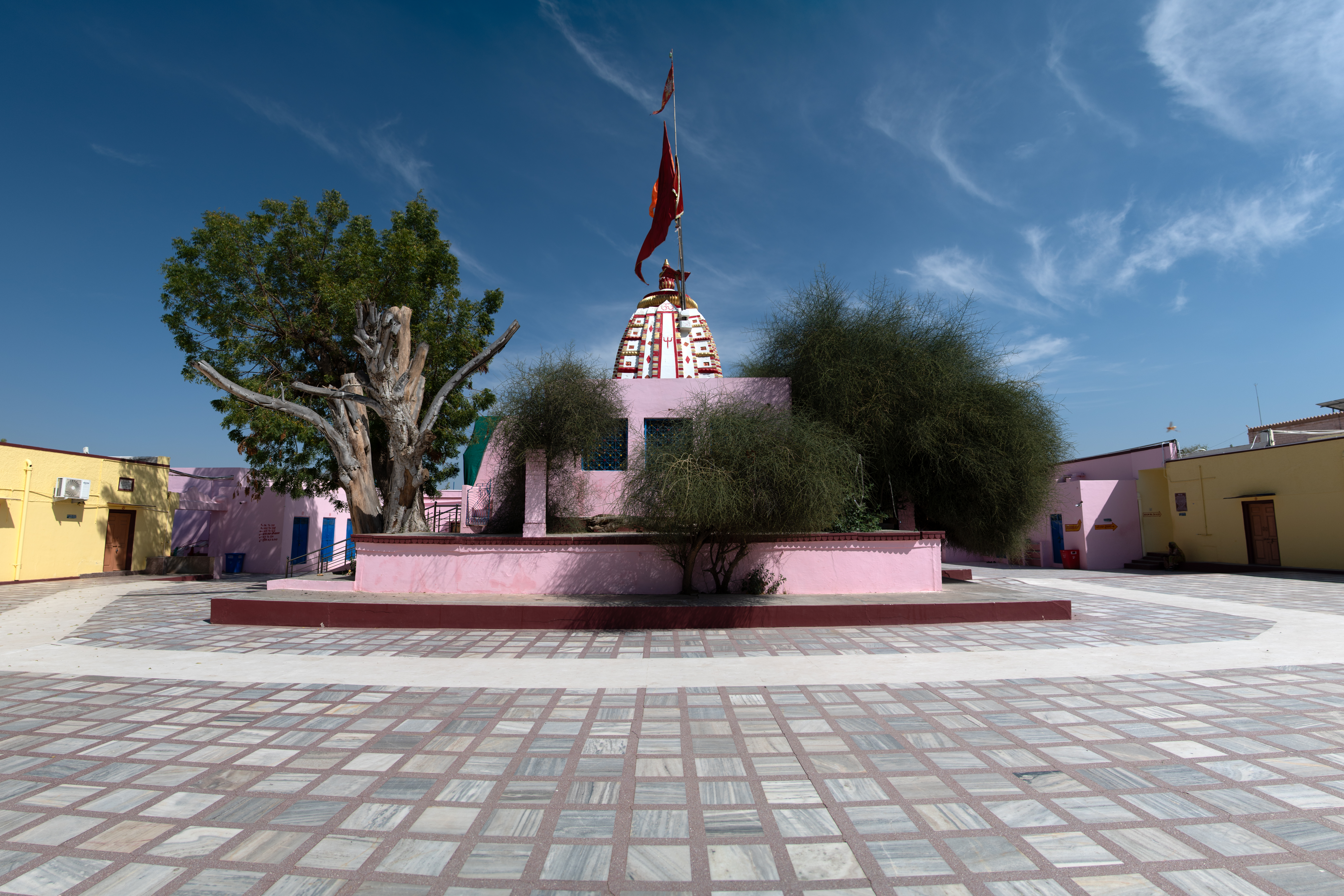 View of the Suswani Mata Temple from the back side, consisting of the newly added walls surrounding it along with the trees that are considered sacred by devotees. The original shikhara can be seen of the temple.